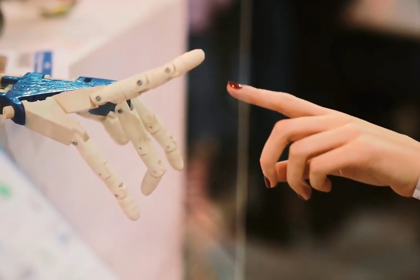 Une jeune femme pointe le doigt vers la main d'un robot.